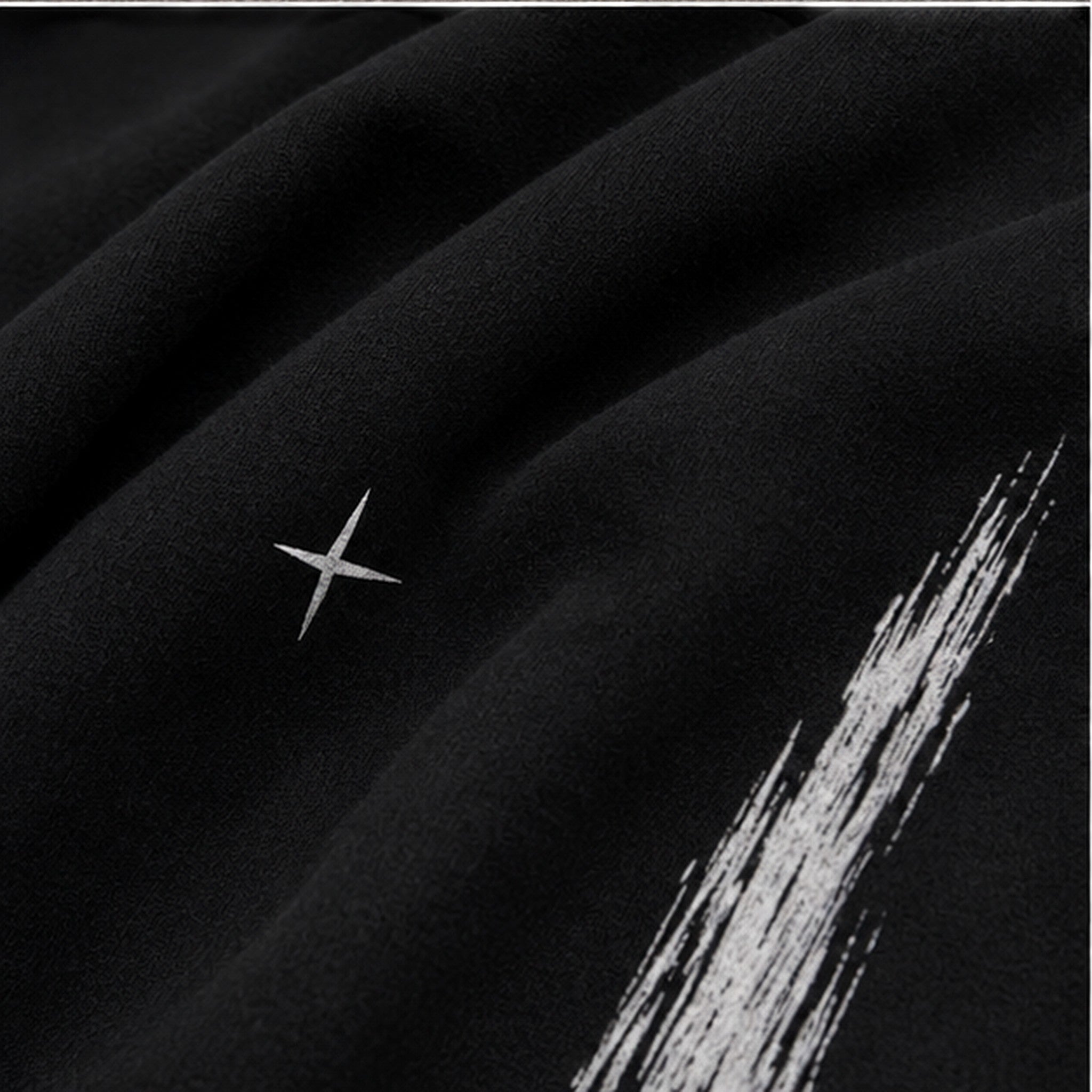 Vanta black fleece sweatpants fabric detail with white graffiti-inspired brushstroke print and small star accent