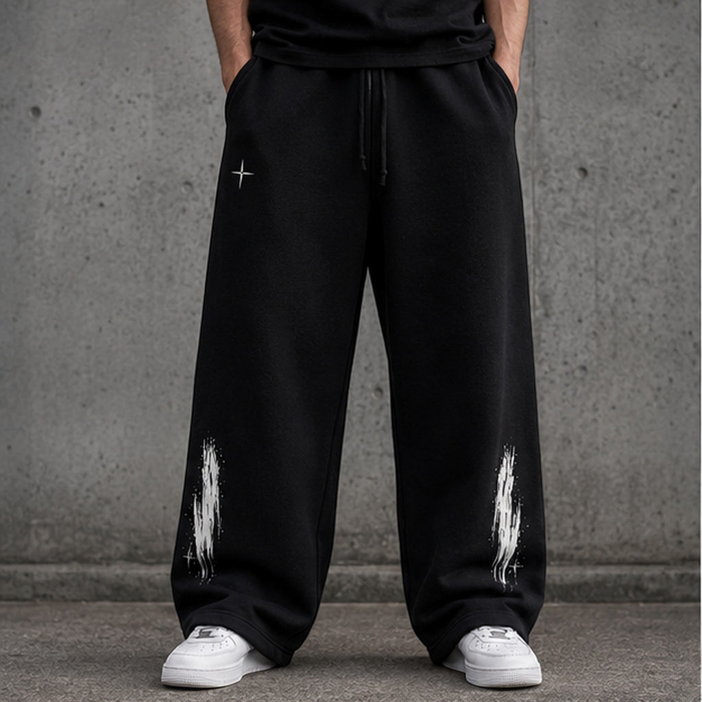 Vanta unisex black fleece sweatpants with an oversized fit, drawstring waist, and white graffiti-style leg prints.